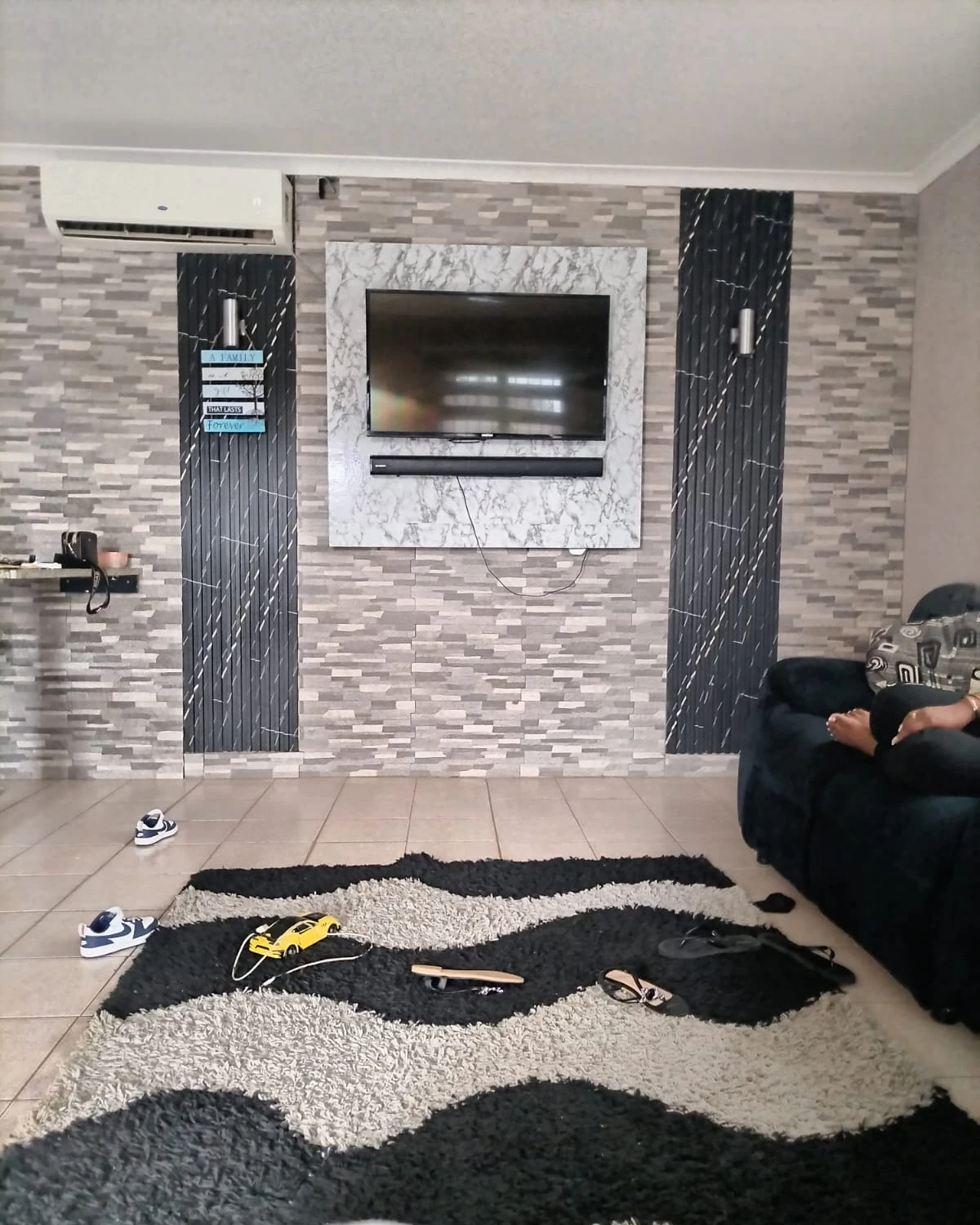 Living room feature wall with stone cladding and black fluted slat panels