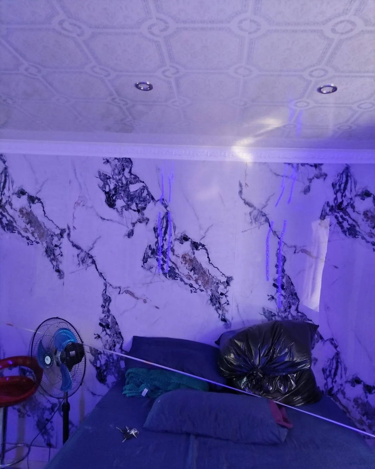 Bedroom wall with gloss marble panels and PVC ceiling